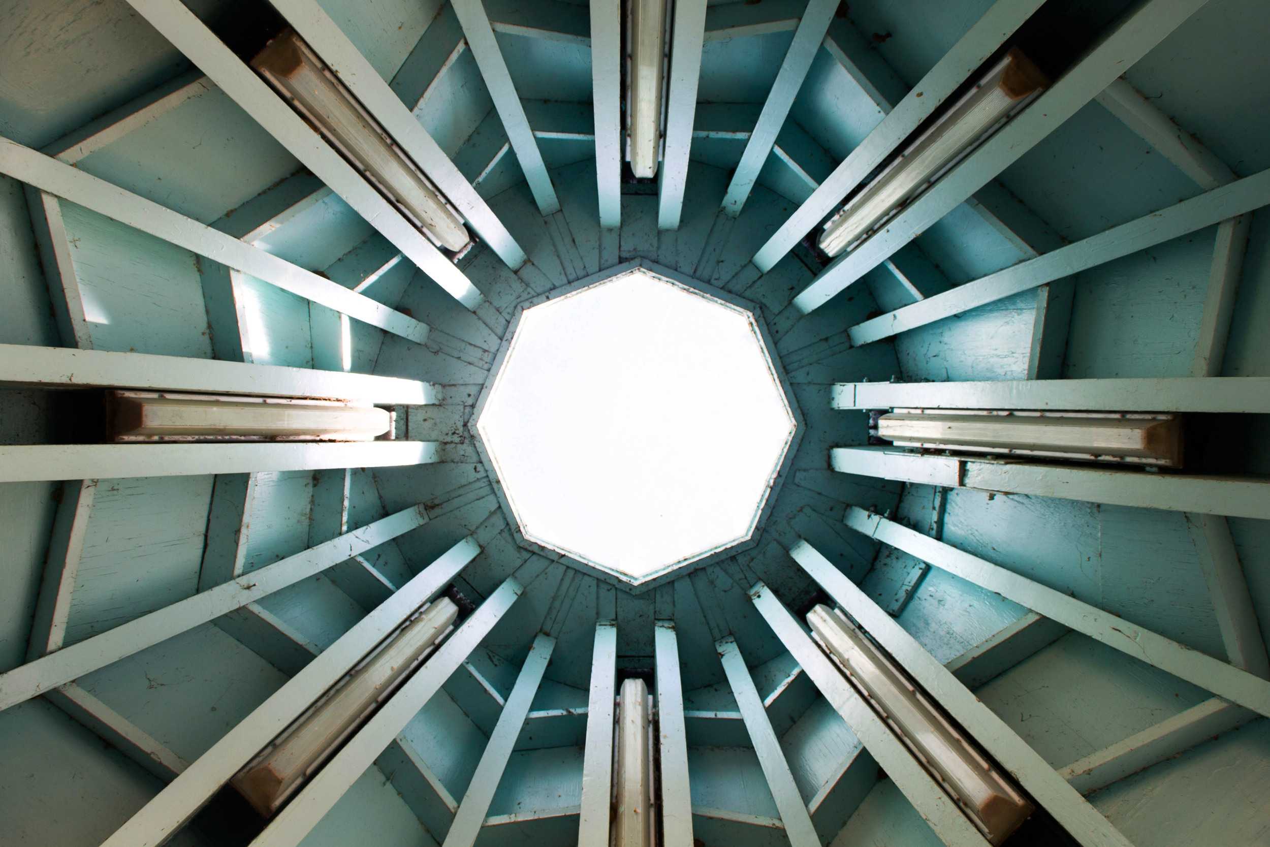  Sunlight peeks through the open top of a gazebo on the town lake running trail, highlighting the bright turquoise roof. 