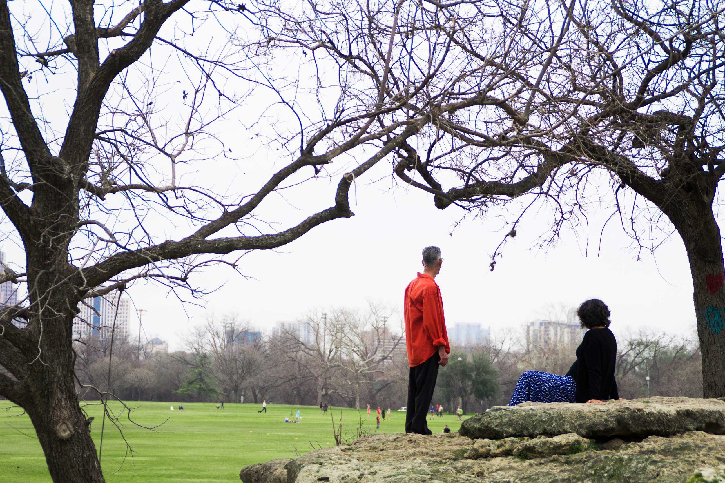  A couple enjoys the warm weather at Zilker Park, as others lounge and play below. 