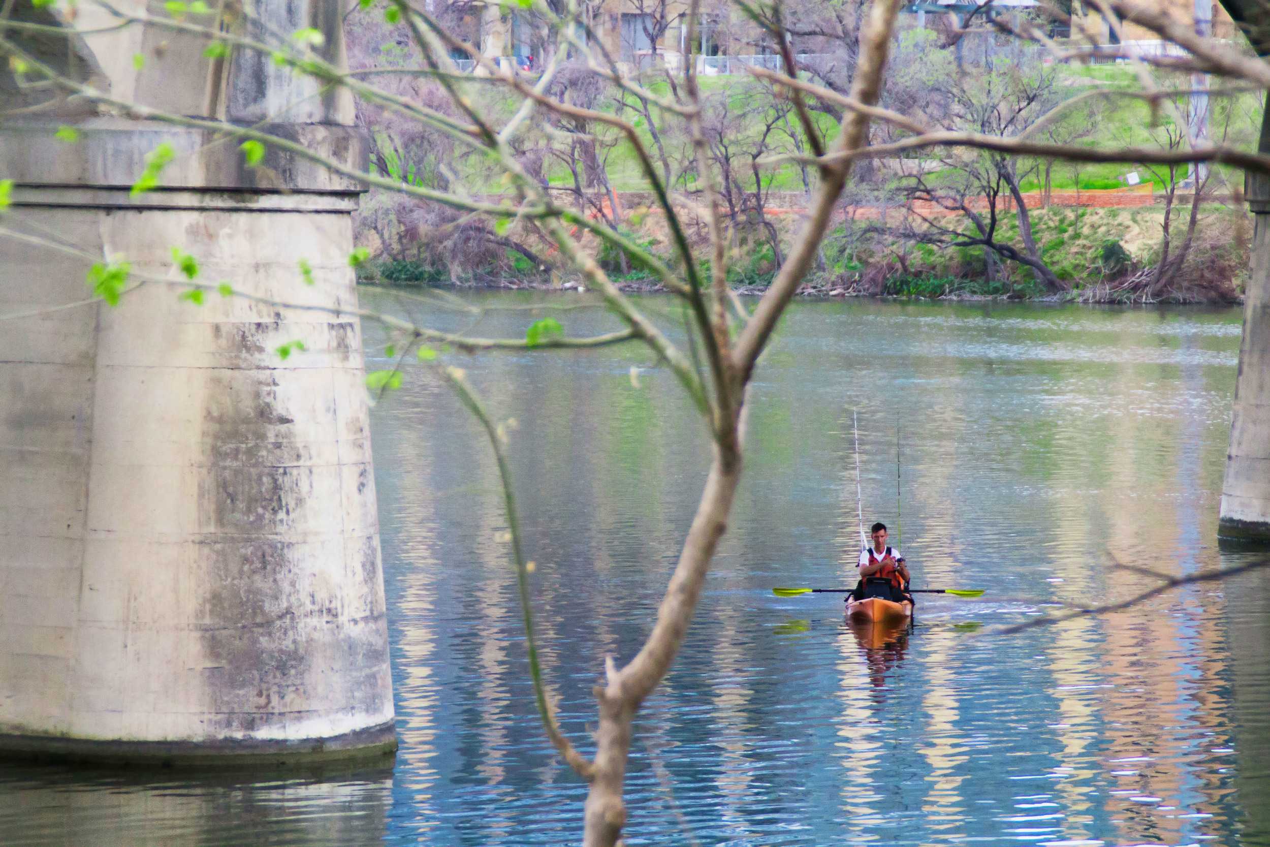  Town lake reflects the vibrant colors of spring time as a kayaker floats, taking advantage of the warm weather. 