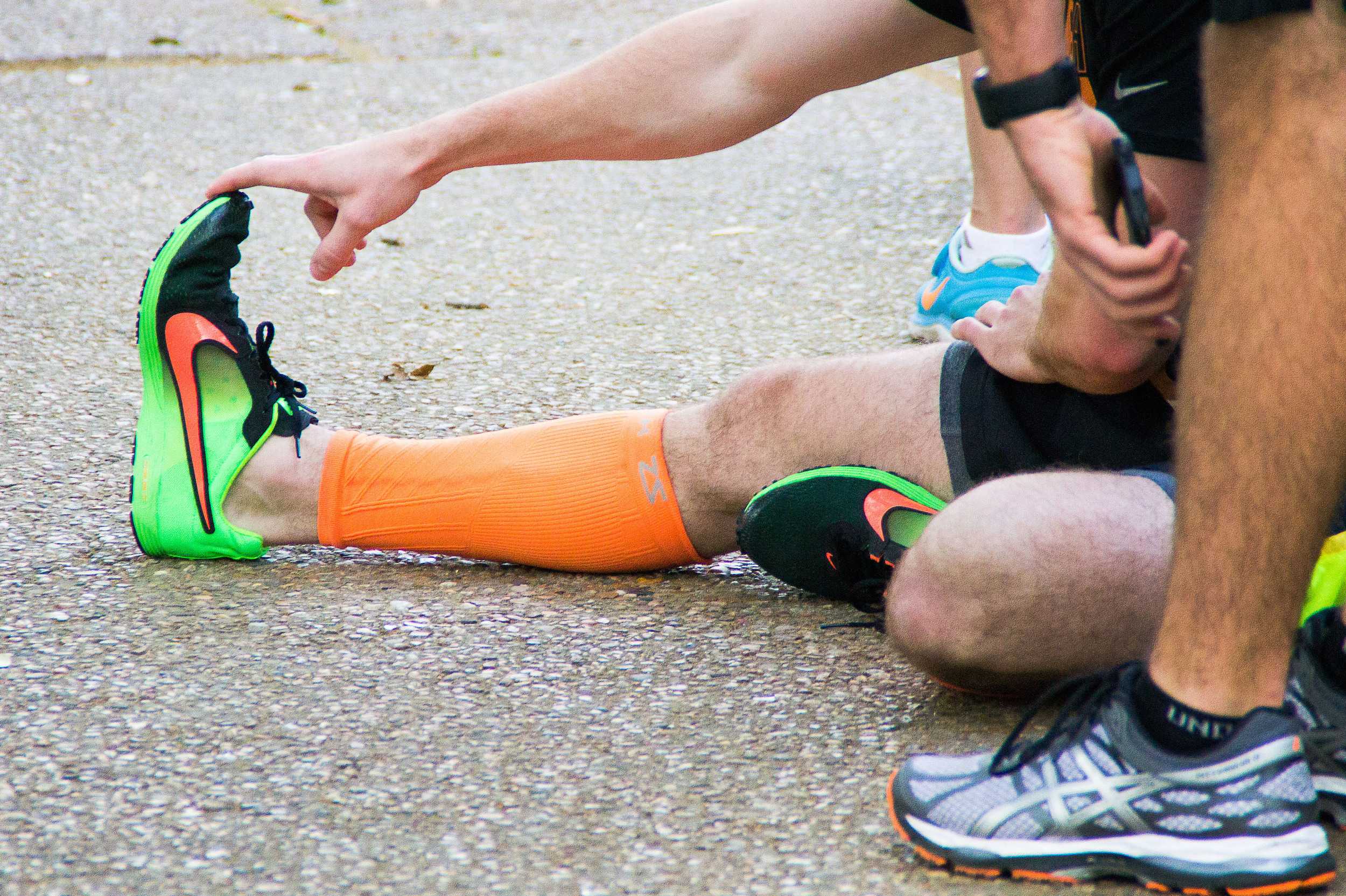  Vibrant sneakers peek out from behind stretching racers, their owner warming up for the 5K round. 