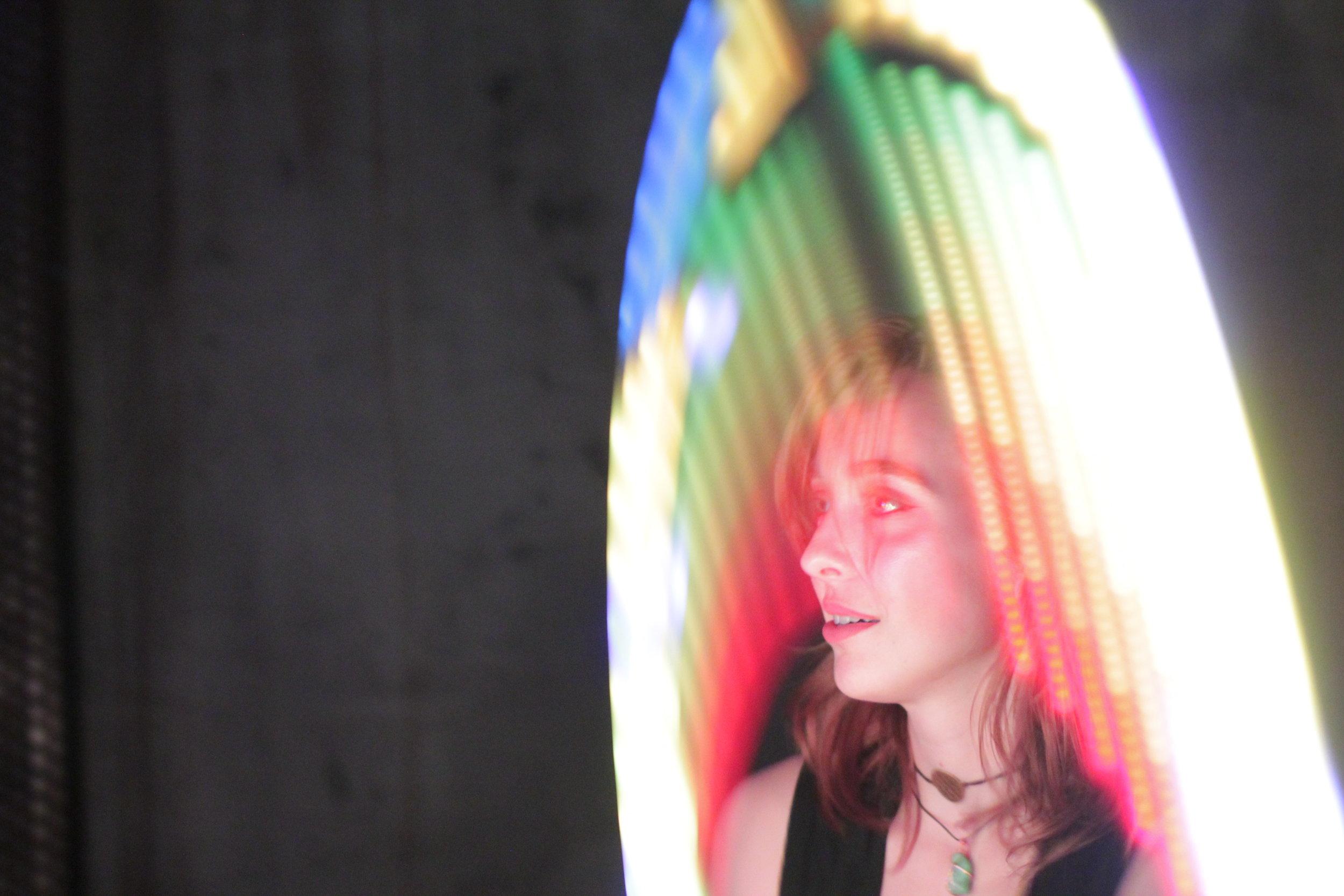   A club goer enjoys the live performance while dancing with a light-up hula hoop.  