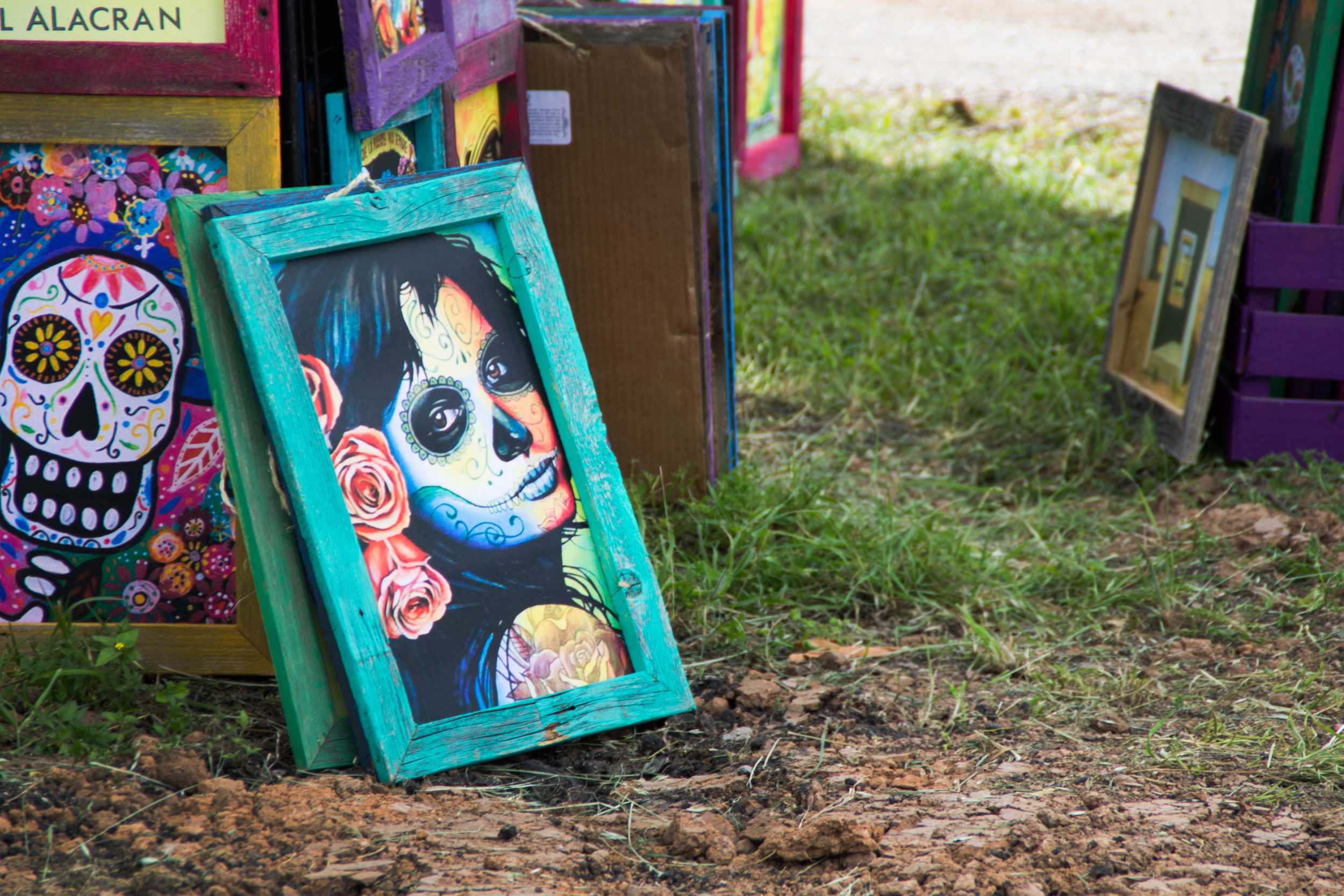  A beautiful painting with a rustic frame leans against a stand amongst other paintings. Many artists took advantage of the Lonestar crowds to promote and sell their works. 