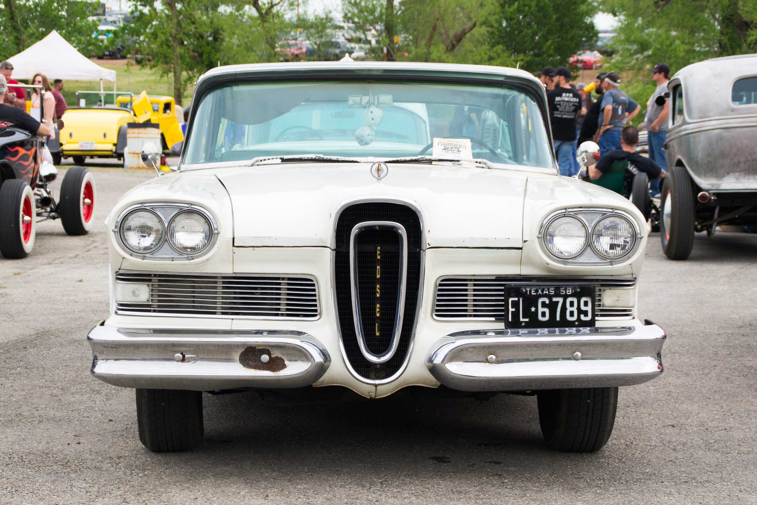  Token fluffy dice dangle from the rearview mirror of this classic white car. 