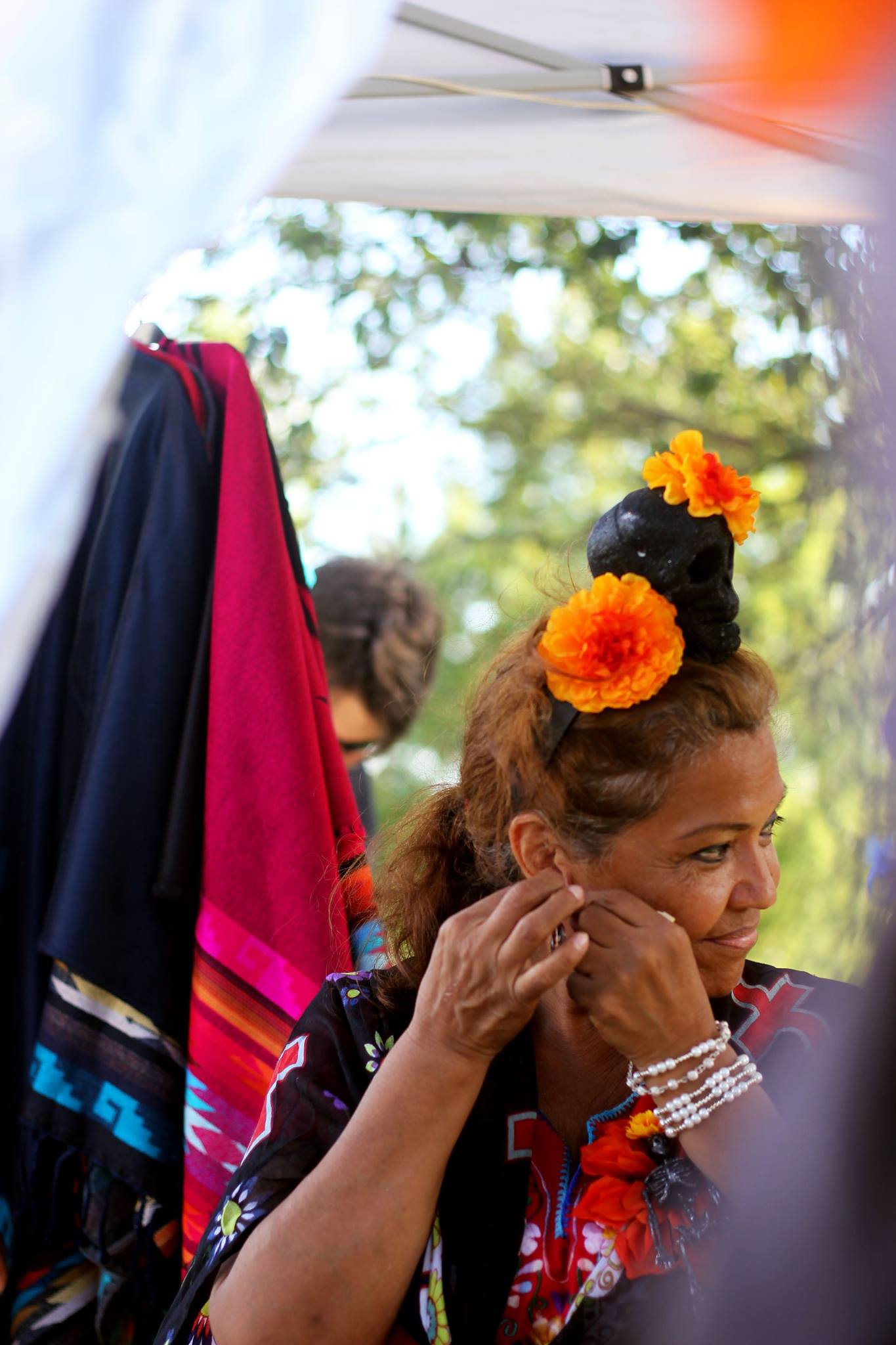   Many vendors made their way to the music festival bringing with them a variety of Mexican knick knacks like bags with the colors of the Mexican flag, traditional embroidered blouses, and jewelry. A vendor looks around while putting on her earrings.