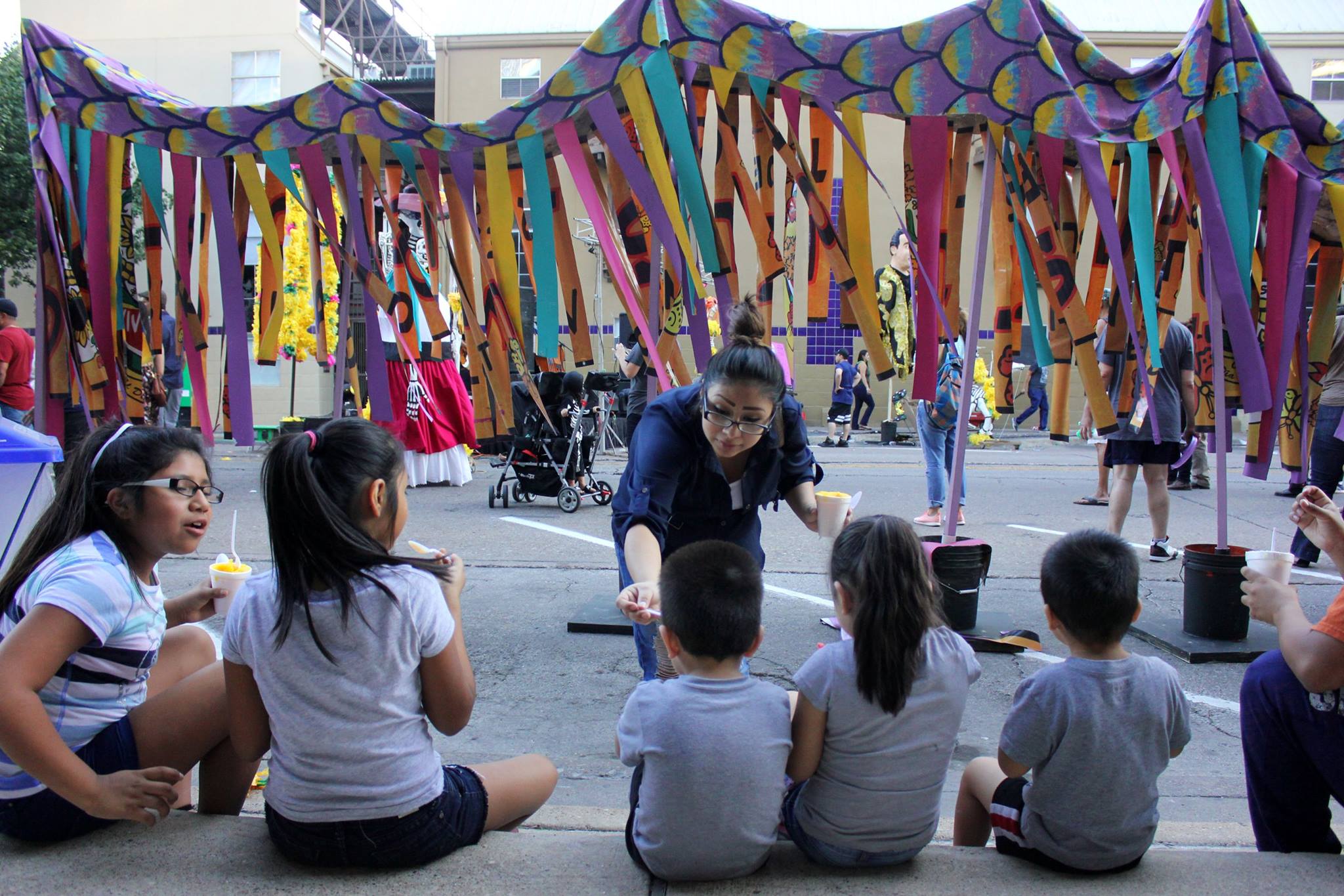   While resting on a sidewalk a family enjoys the live music and food.  