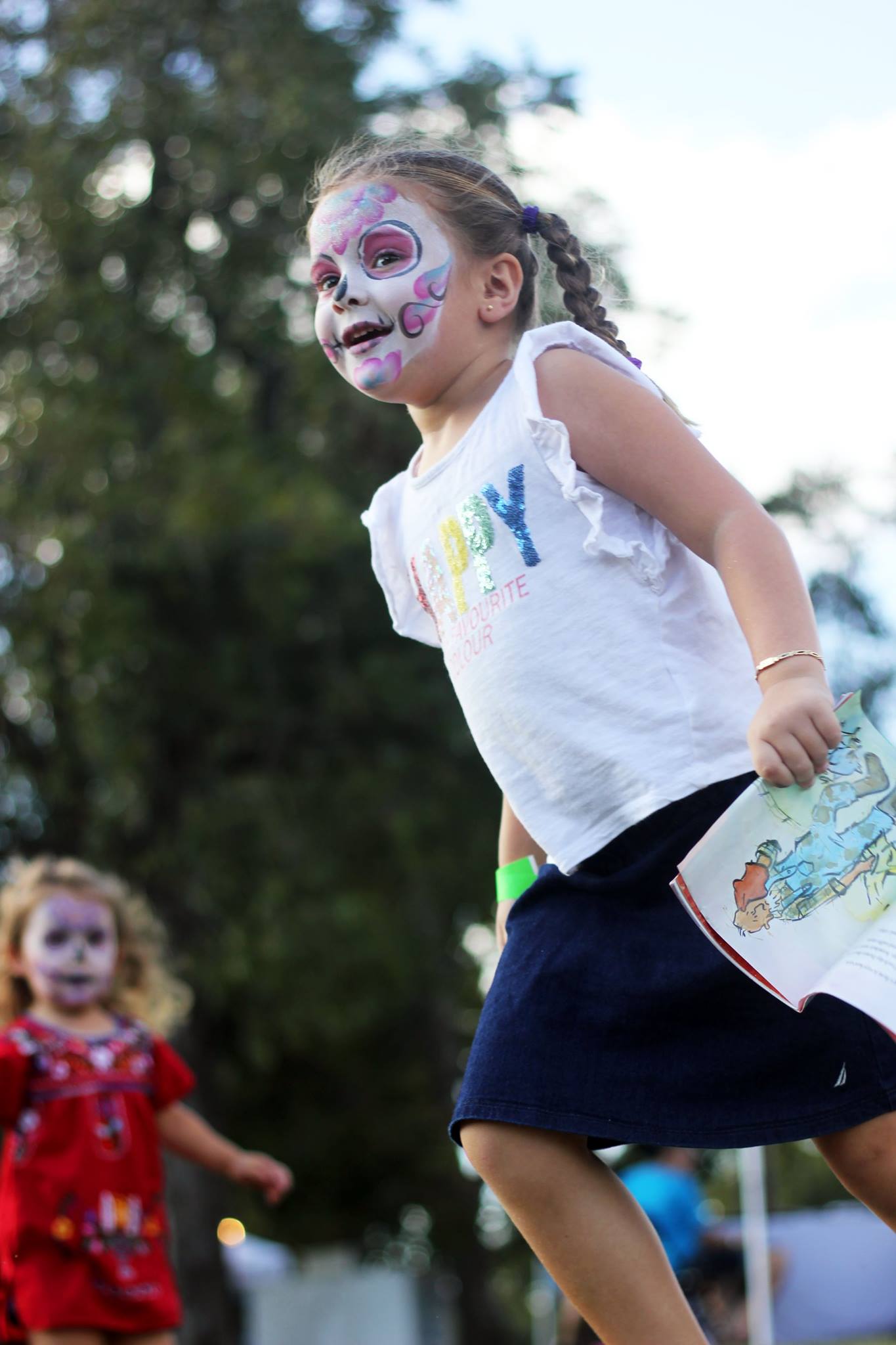   Two children run around after getting their faces painted.  