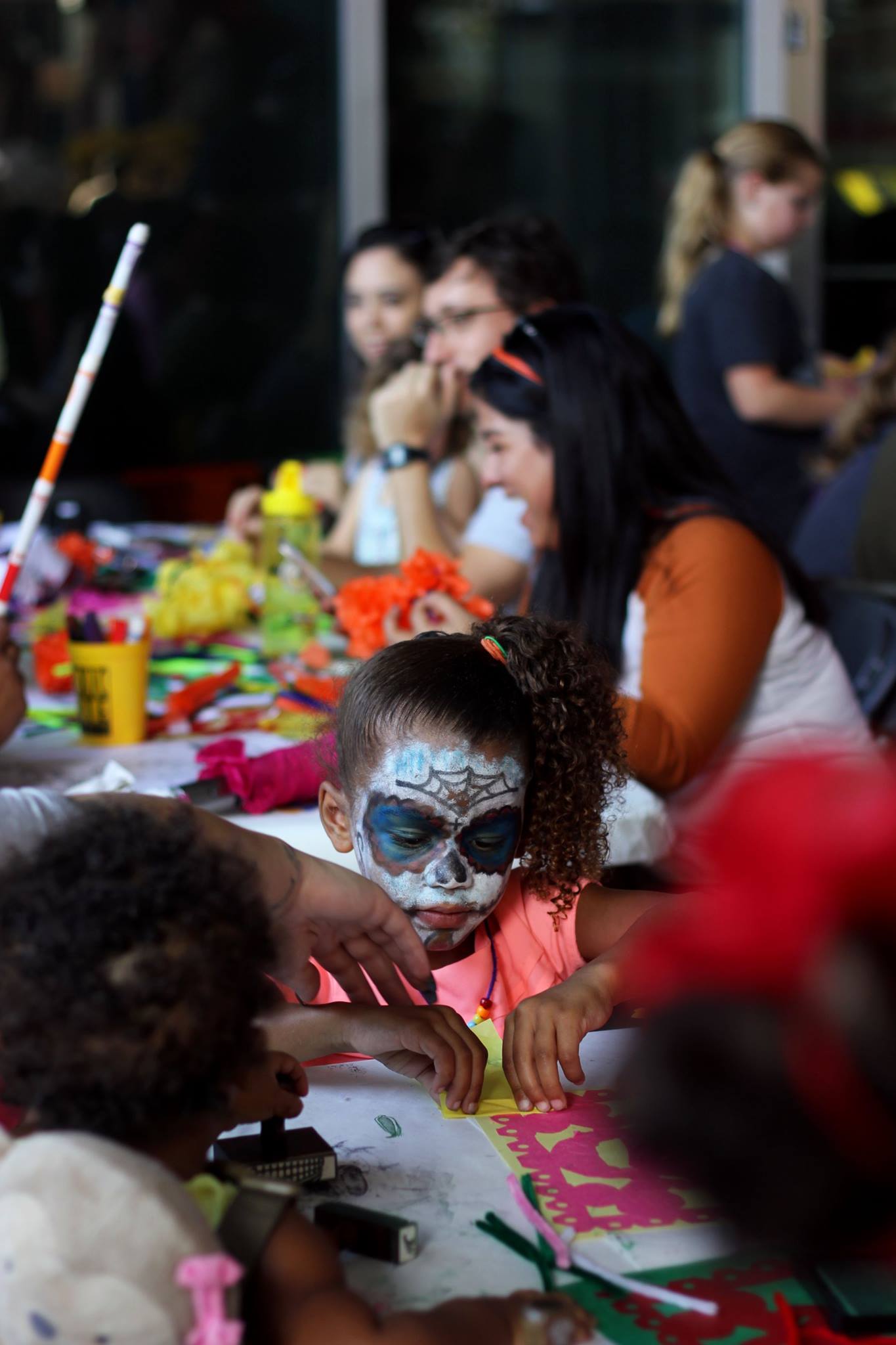   A mother helps her child create her papel picado.  