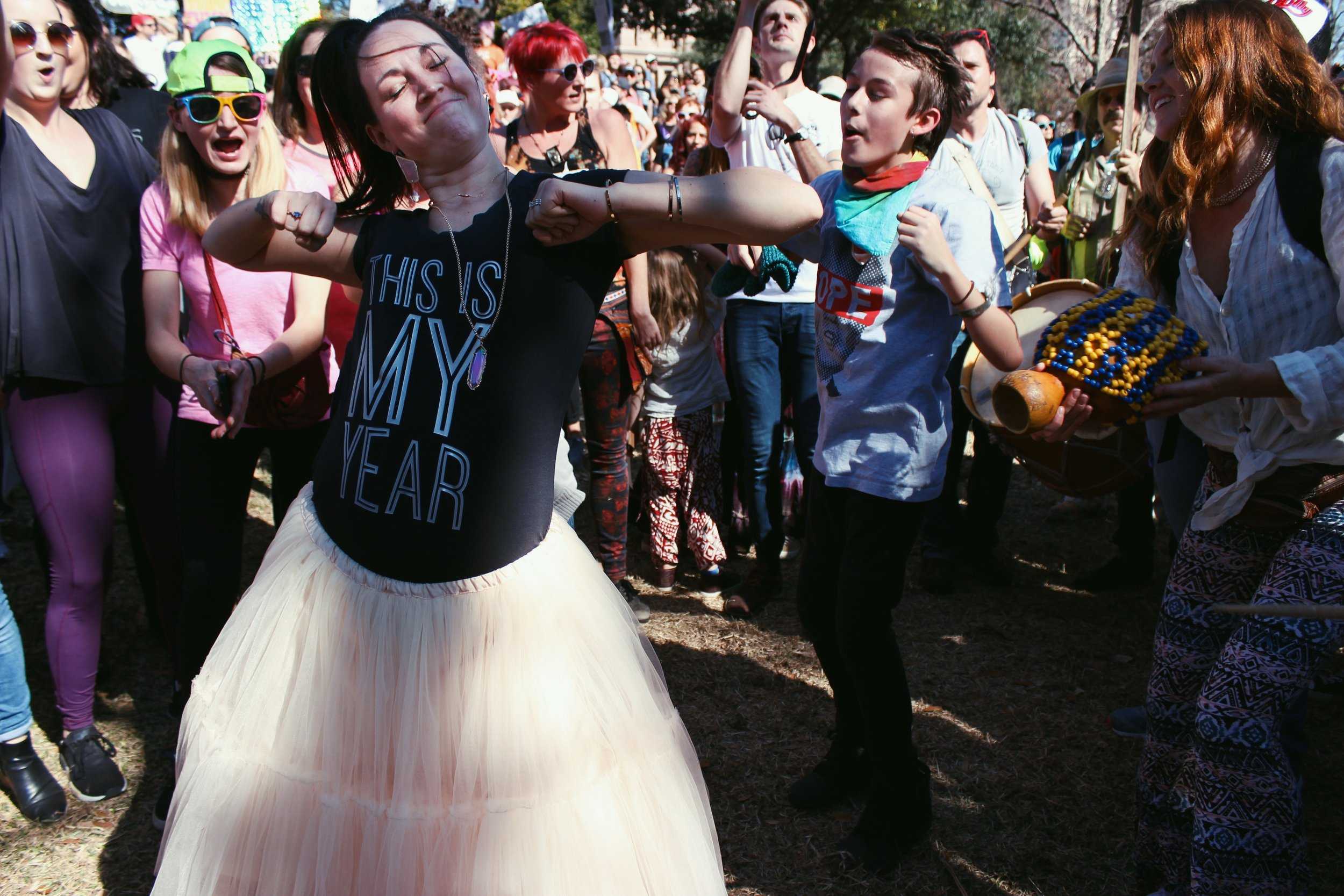   A woman takes the spotlight in the middle of a dance circle initiated by drummers filling a corner of the Capitol.  