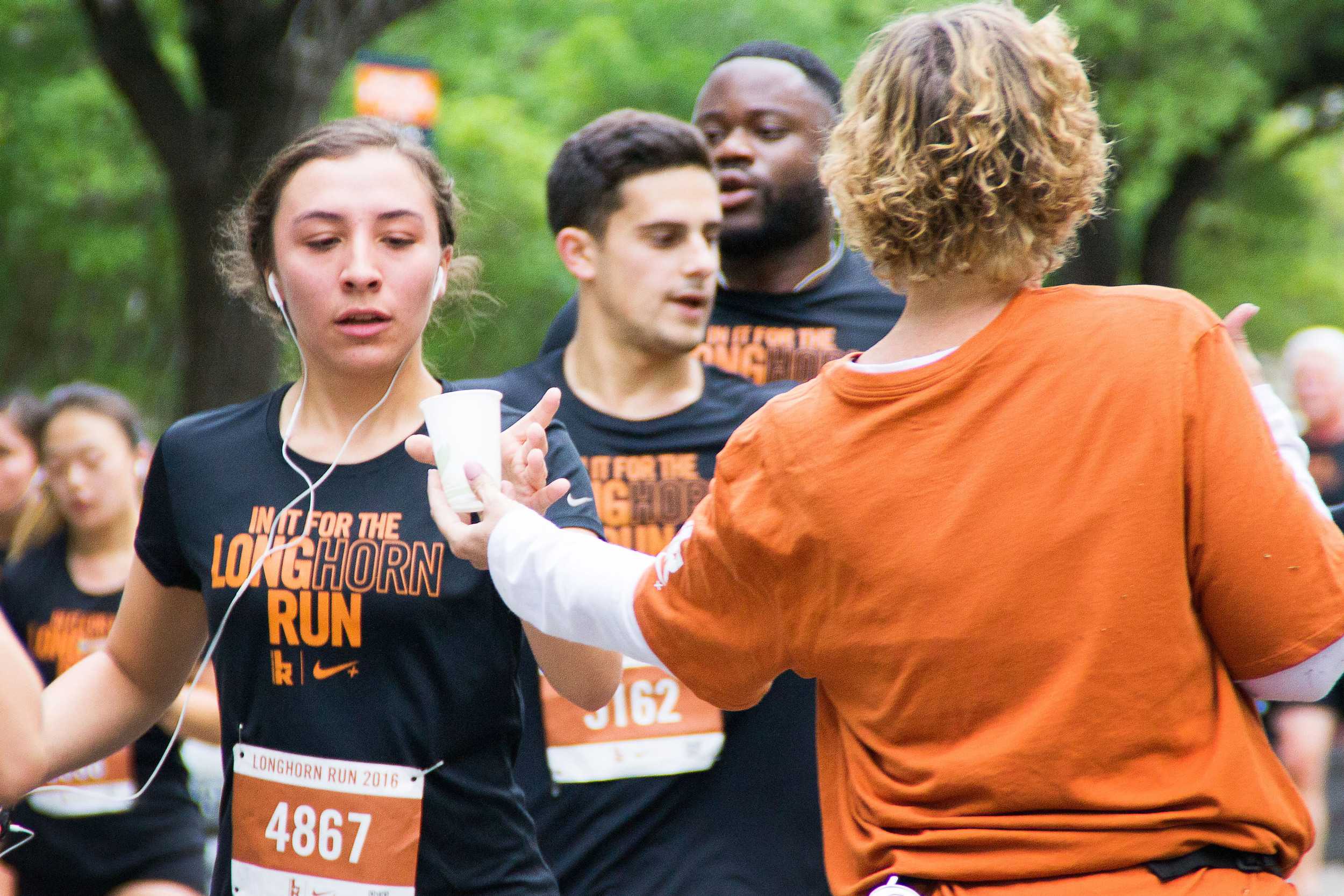  The last leg: an exhausted runner takes a water cup from one of the volunteers at the last water stop until the finish line. 