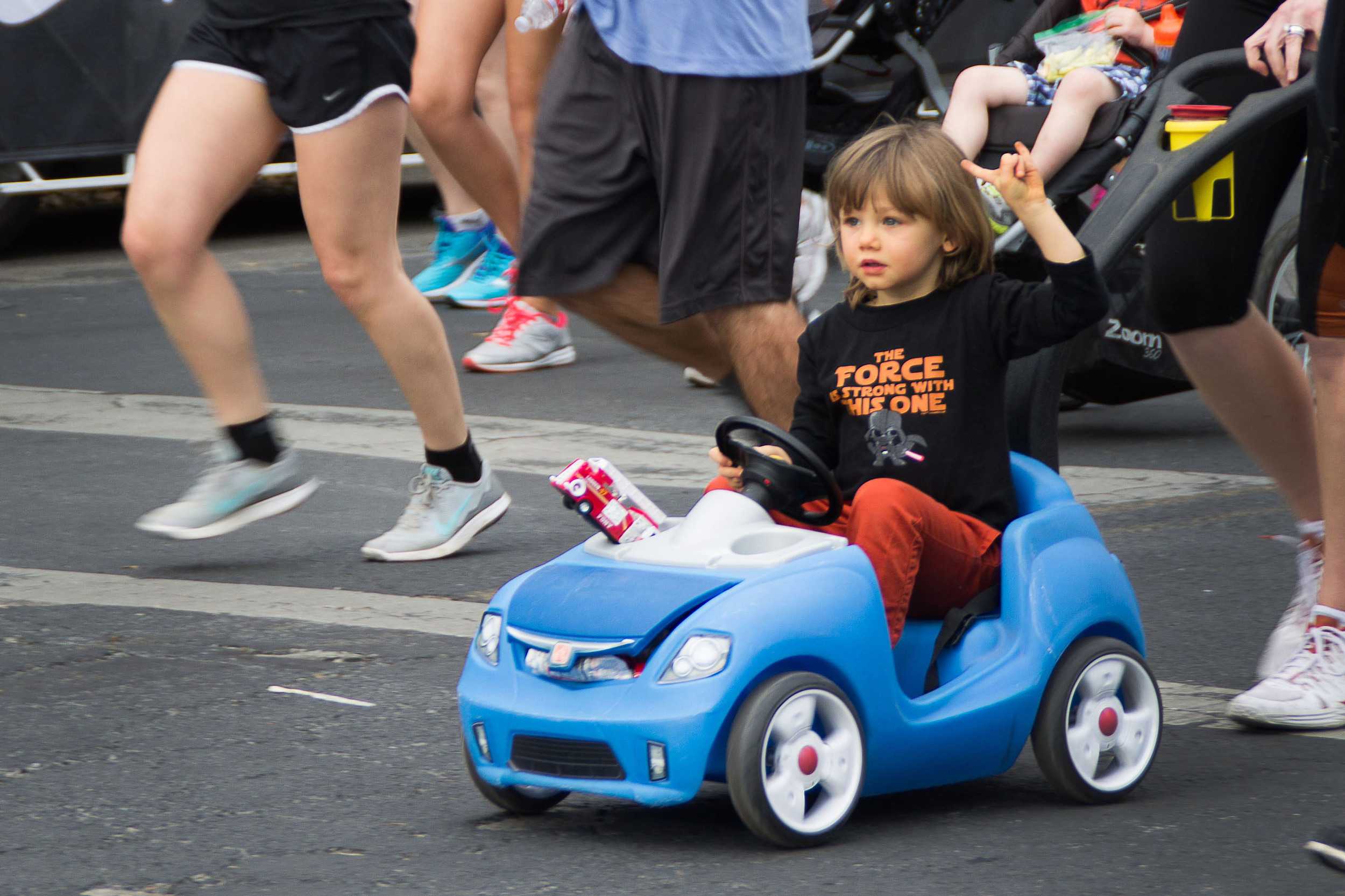  A bewildered-looking child throws his horns up, and is pushed in a car at the starting line of the race. 