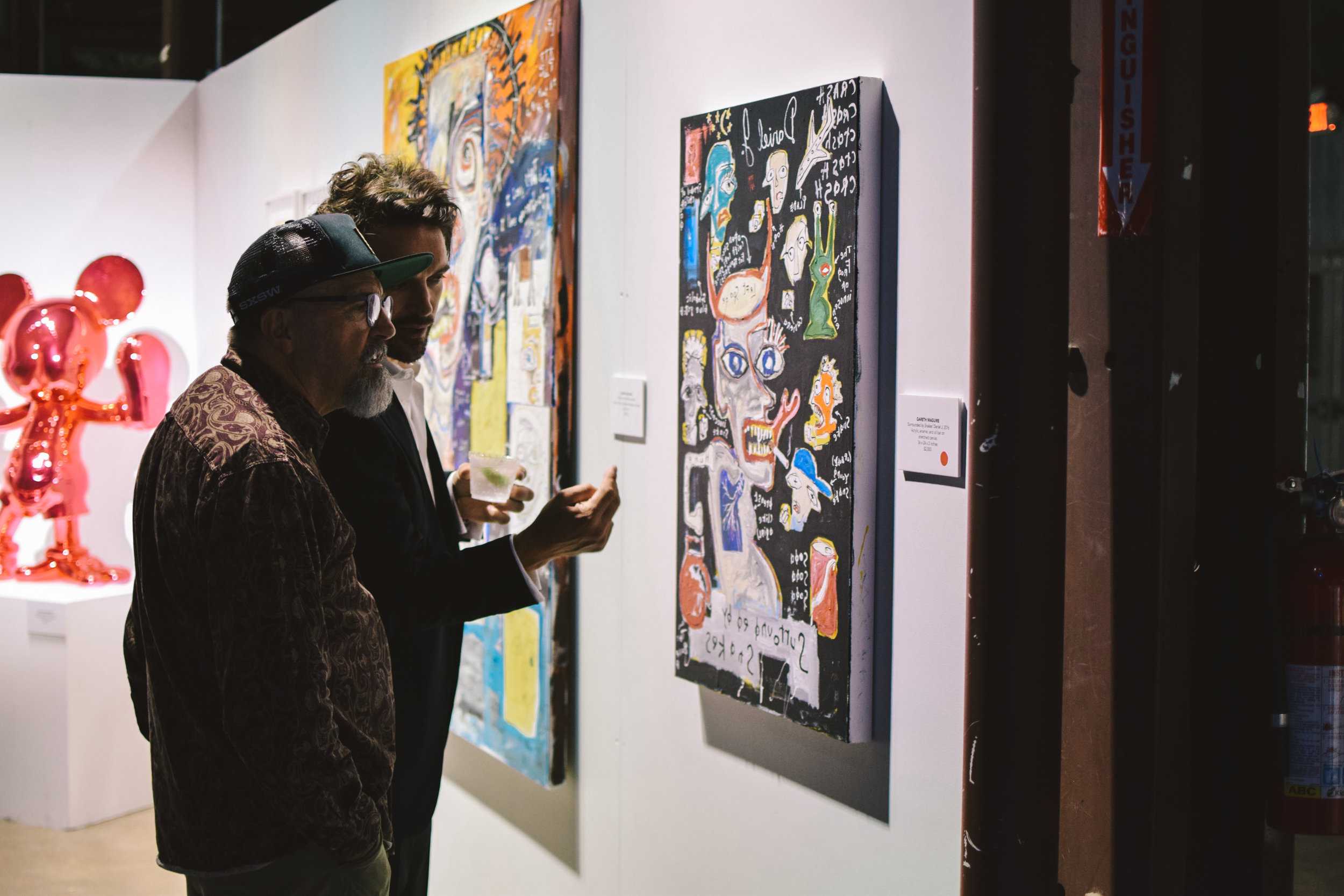   Artist Gareth Maguire discusses his piece “‘Surrounded by Snakes’ Daniel J” with attendee.  