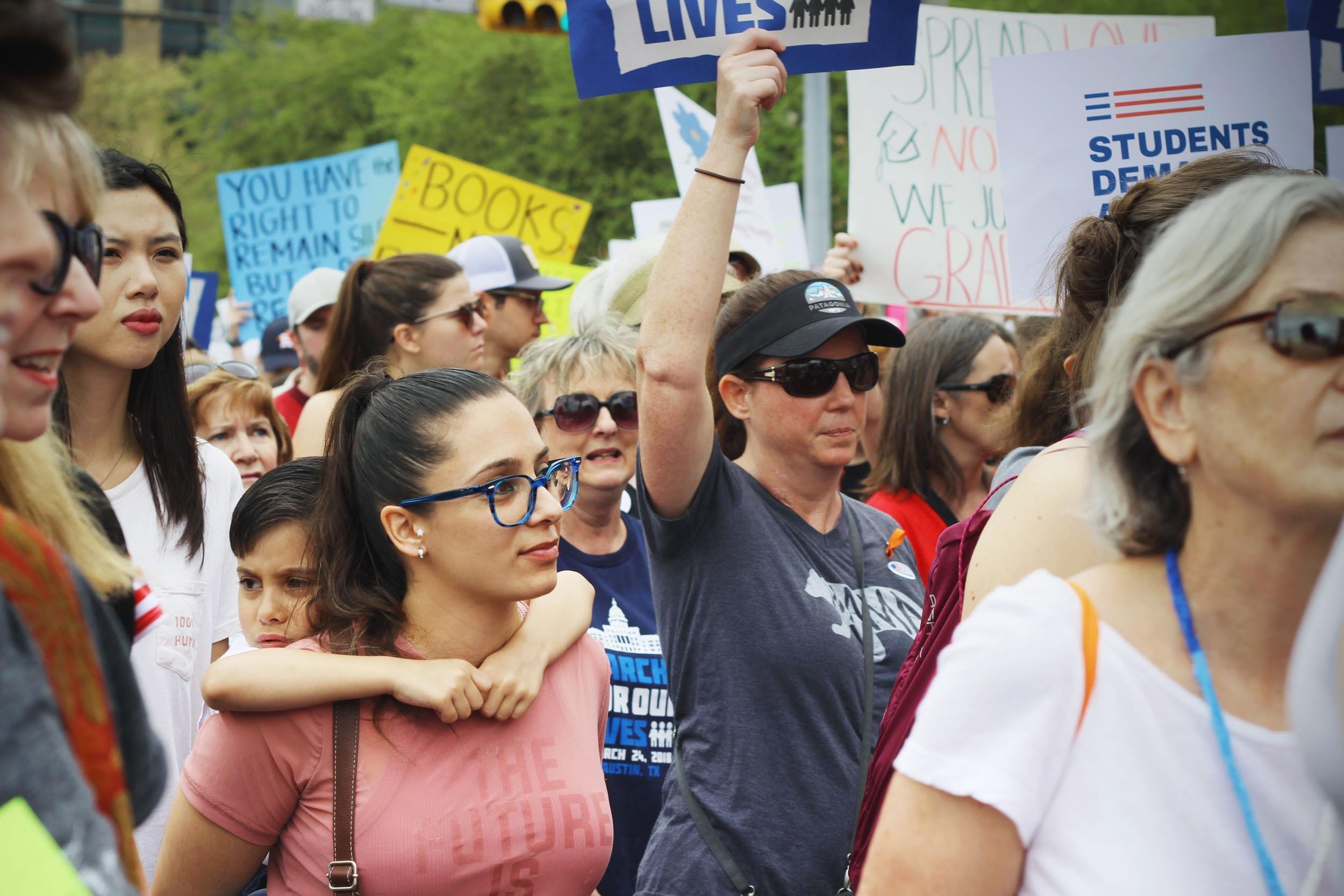   A young boy puts his arms around his mother as they continue to march.  