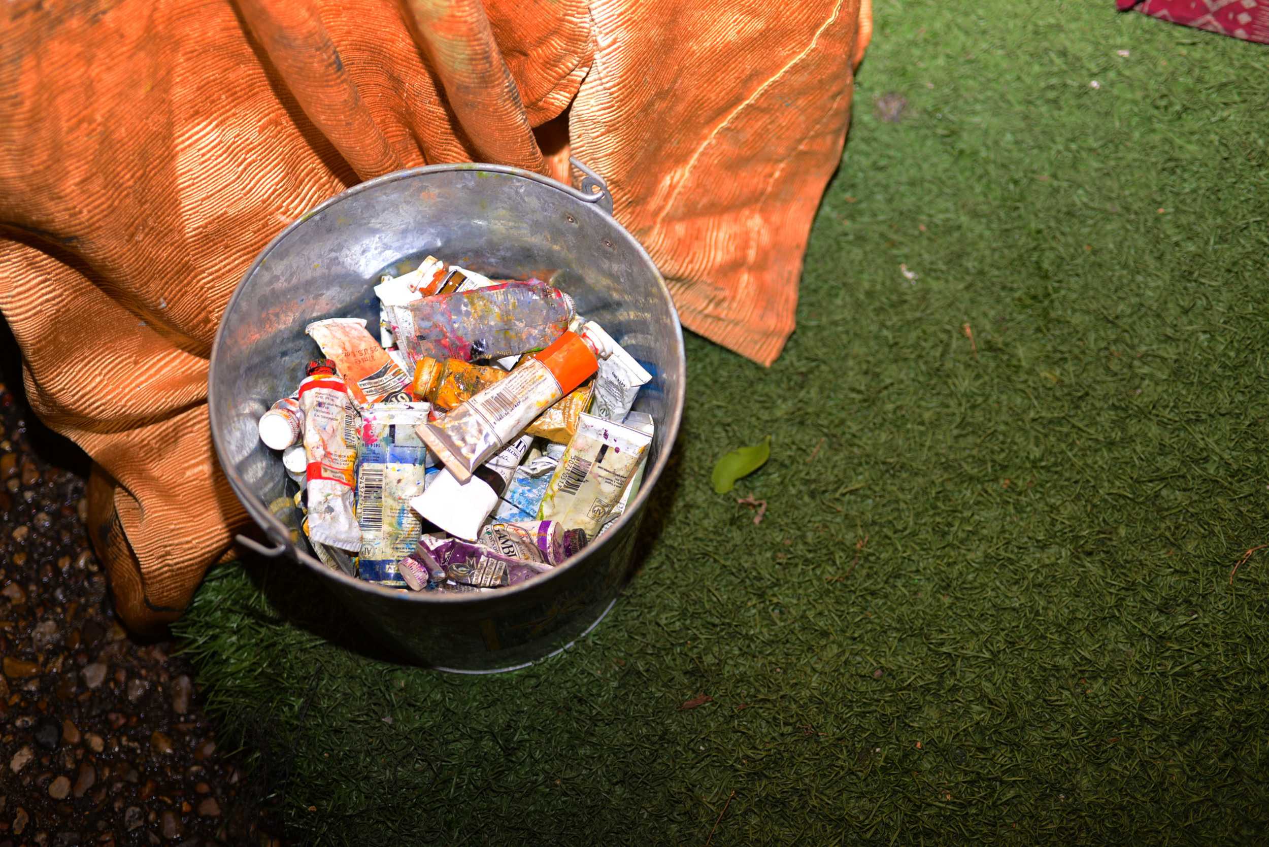   A bucket of paint serves as an artist’s right hand at Empire’s backyard art show. Photo by Dahlia Dandashi.  