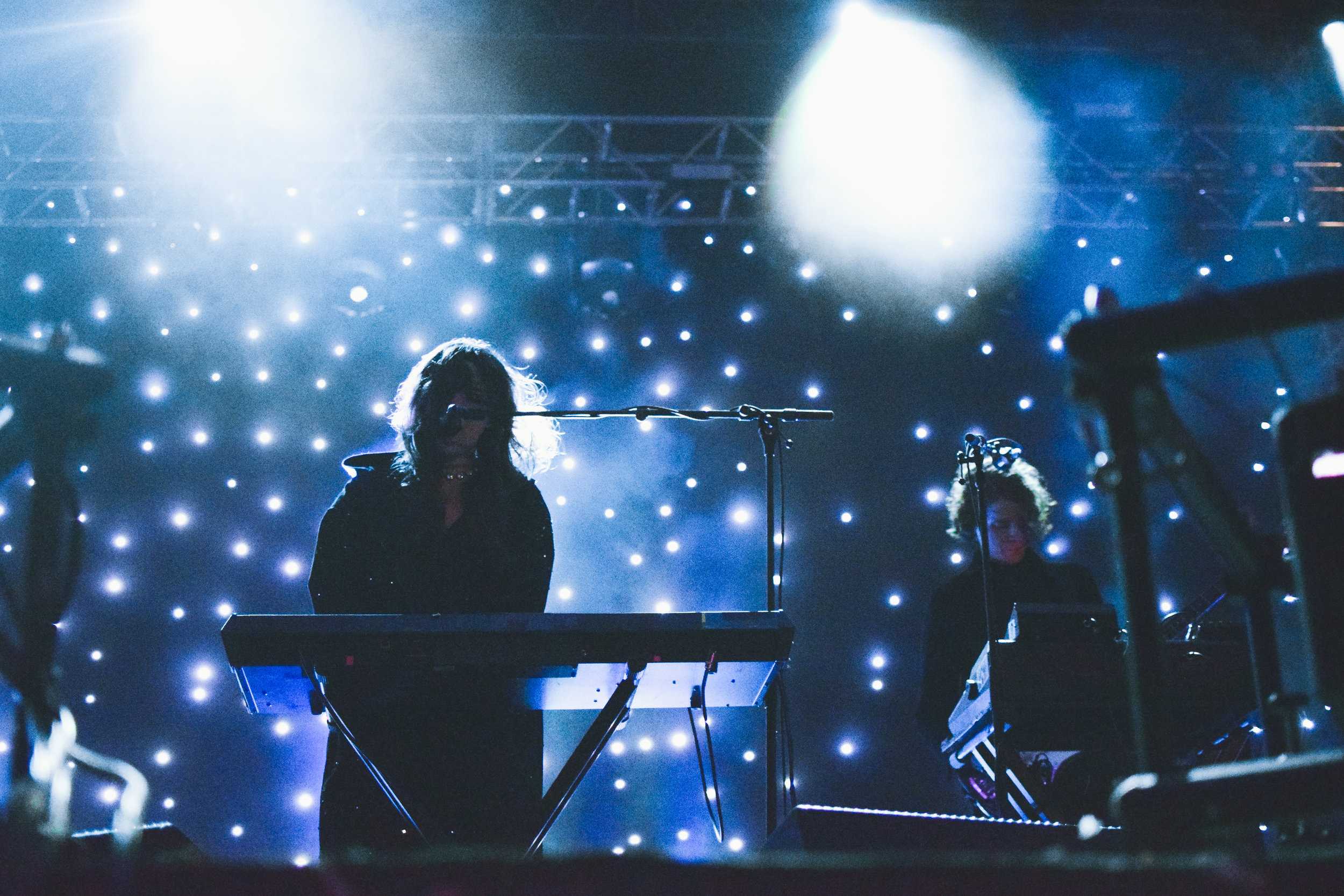   Victoria Legrand of Beach House looks mysterious in her dark cloak and starry background.  