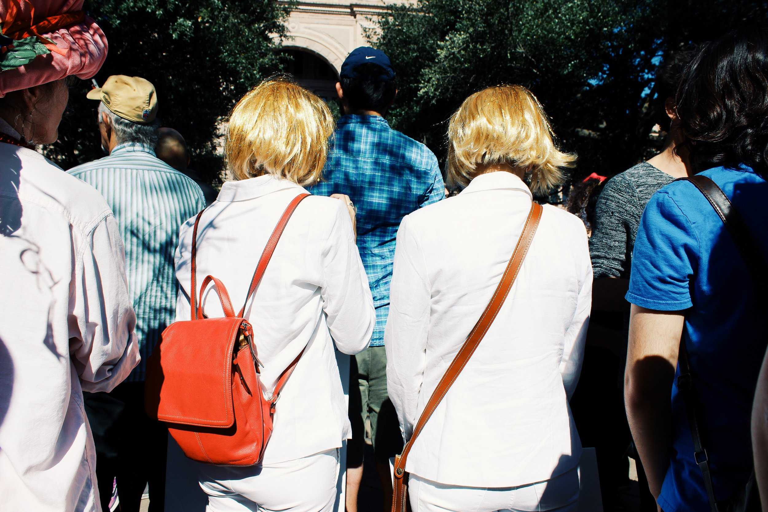   Two women dressed to look like Donald Trump held signs, one reading, “You can’t comb over sexism.”  