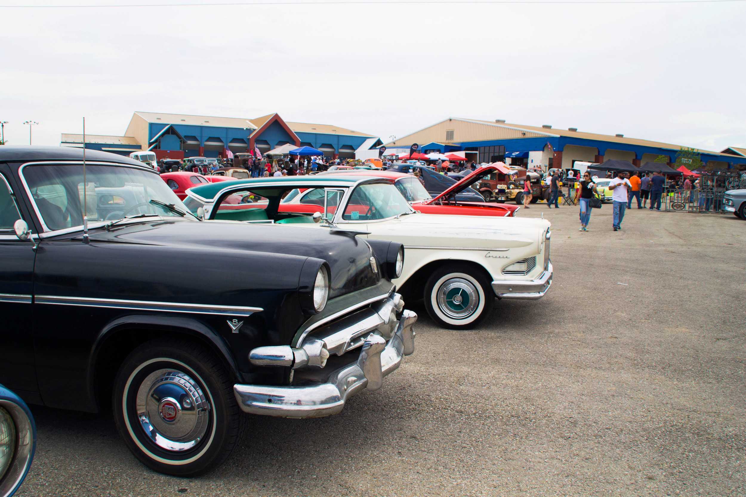  Spectators mill around in the background of the Lonestar Round Up, glossy cars lined up in a row with care. 