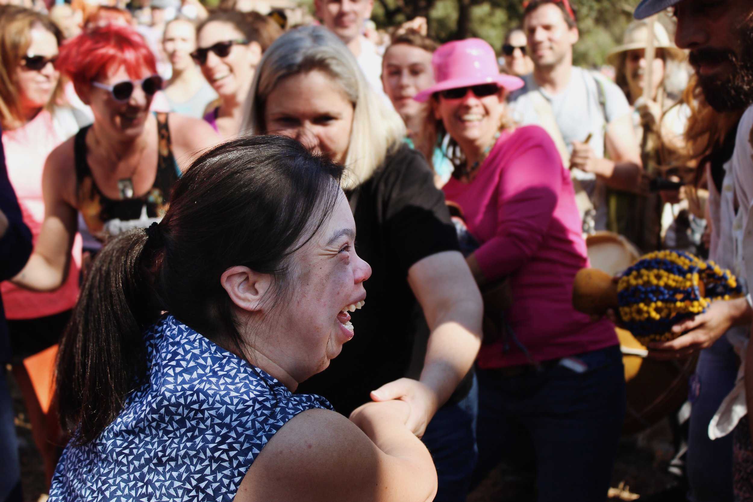   A woman joins people of all ages dancing to the upbeat music of drums.     