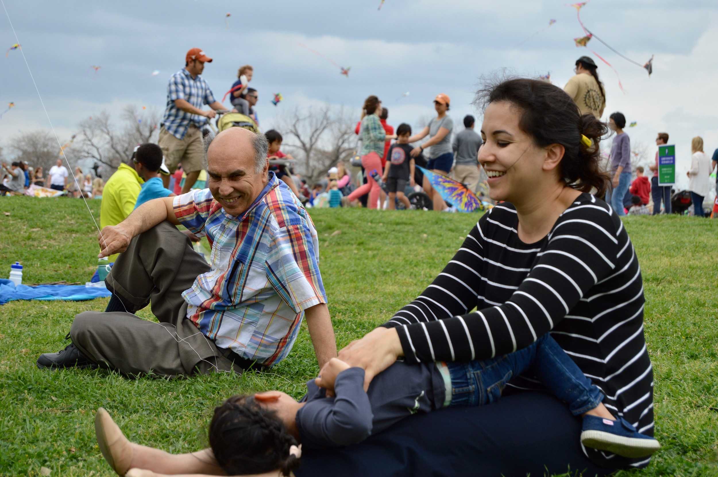  Shameem tickles her daughter while they sit in the grass. 