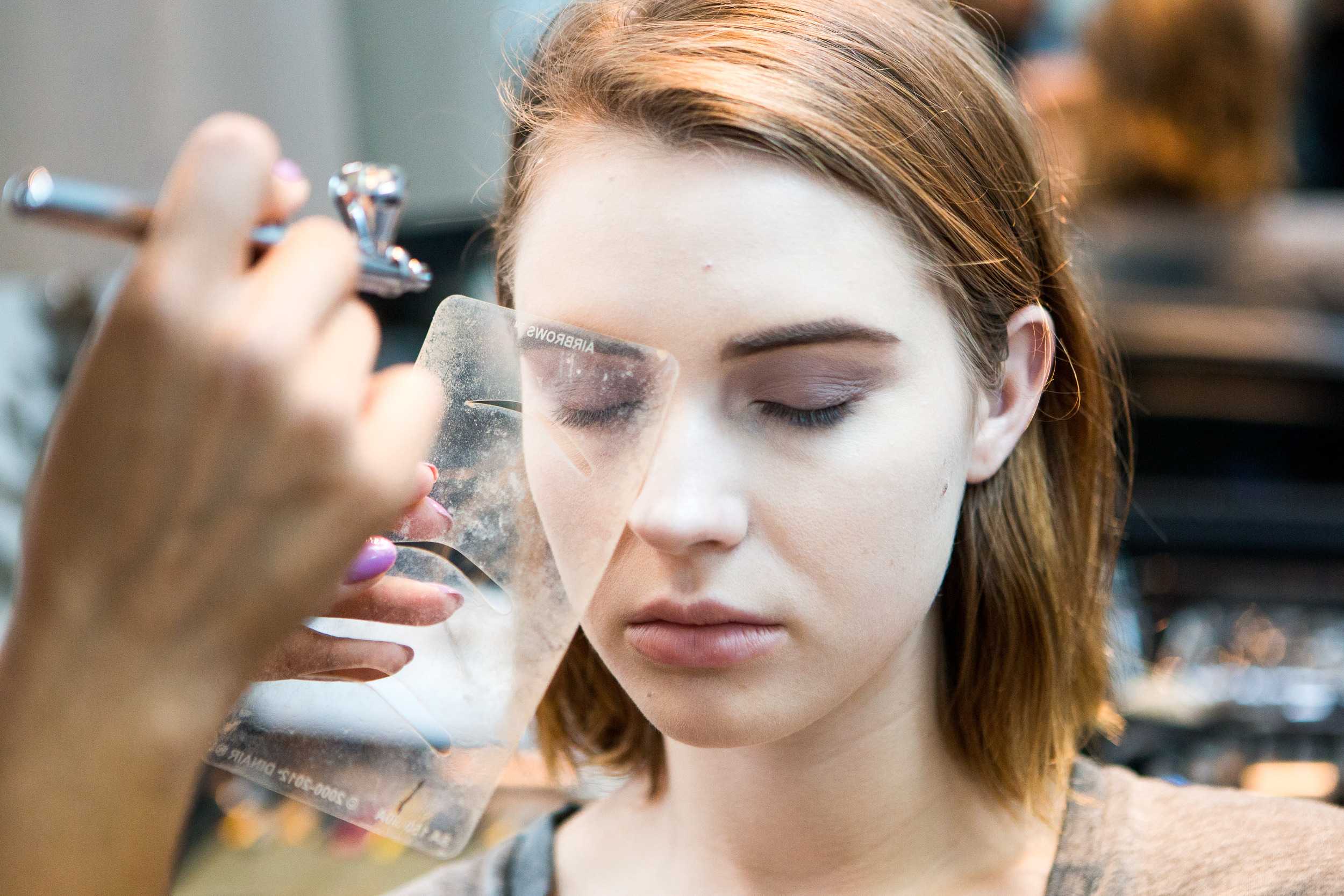   Makeup artist Lauren Garcia applies makeup to model Anna Cash with her airbrush makeup gun.   