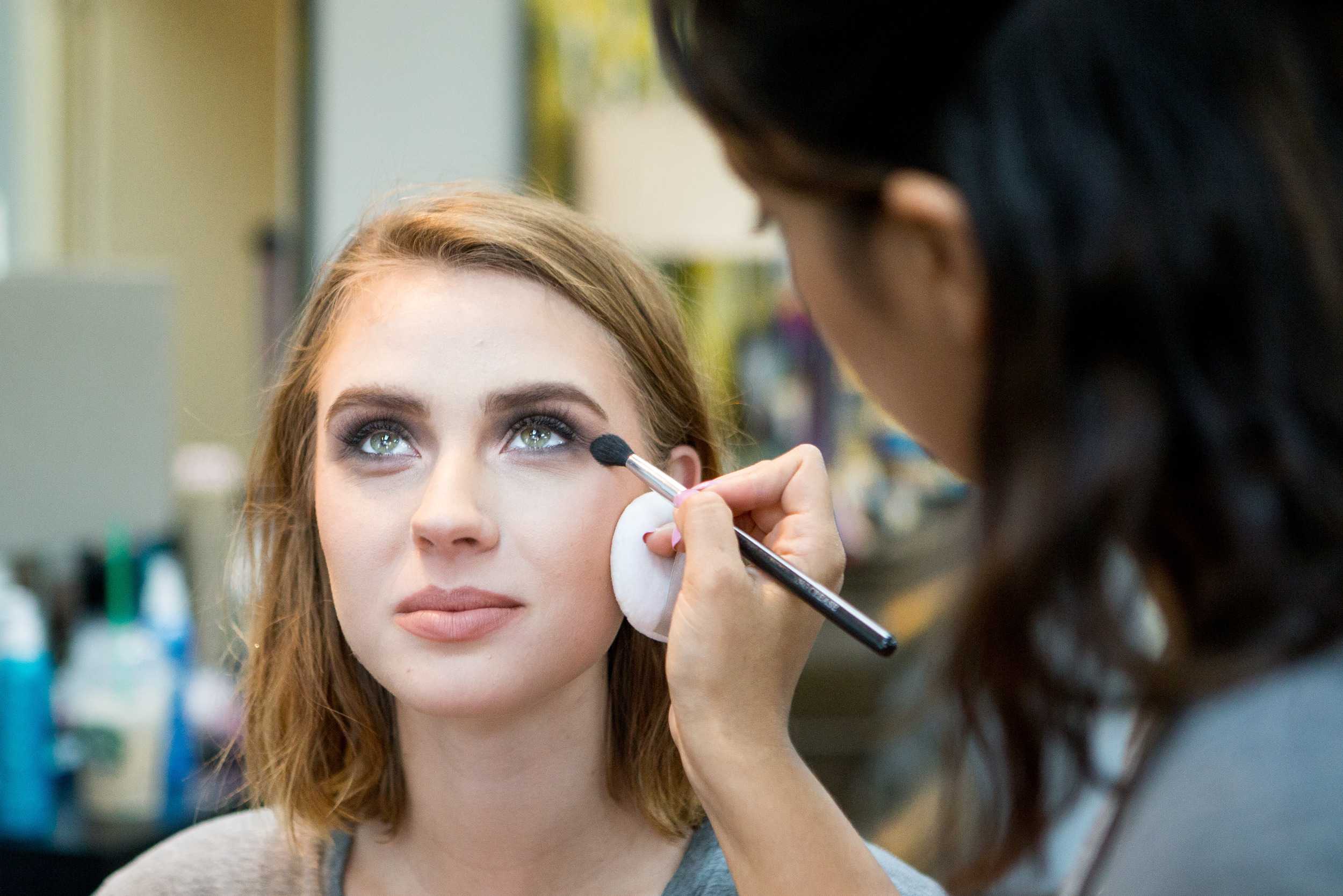   Makeup artist Lauren Garcia applies the finishing touches to model Anna Cash before she is turned over to hair stylist Michi Lafary.  