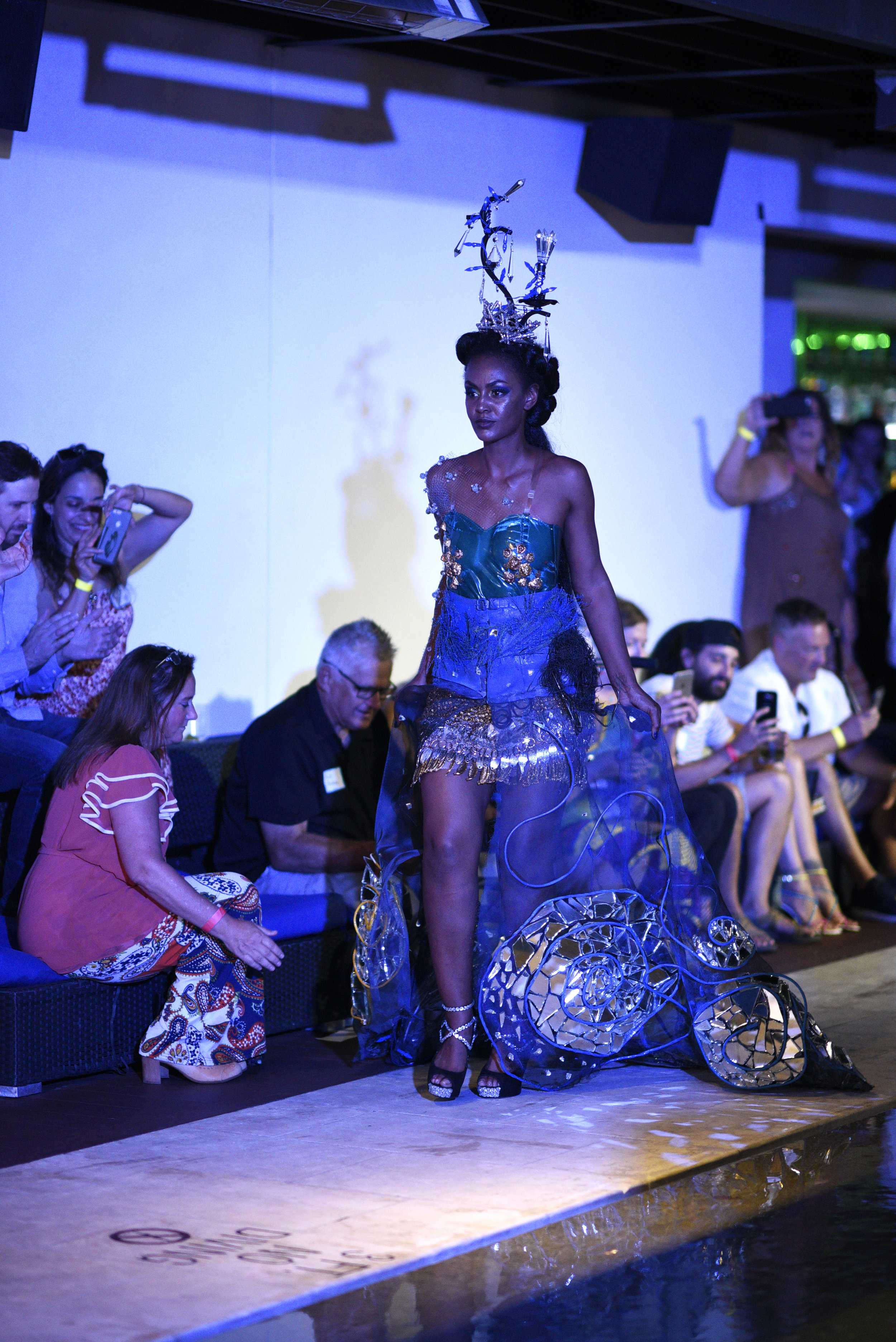   Model walks down the runway in an outfit made with pieces of broken mirrors.   