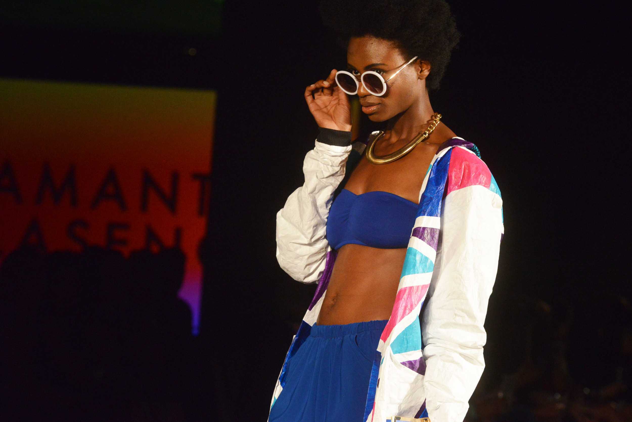   A model for Samantha Plasencia wears a cobalt blue co-ordinate set paired with a color-blocked jacket and accessorized with round white sunglasses. Photo by Dahlia Dandashi.     