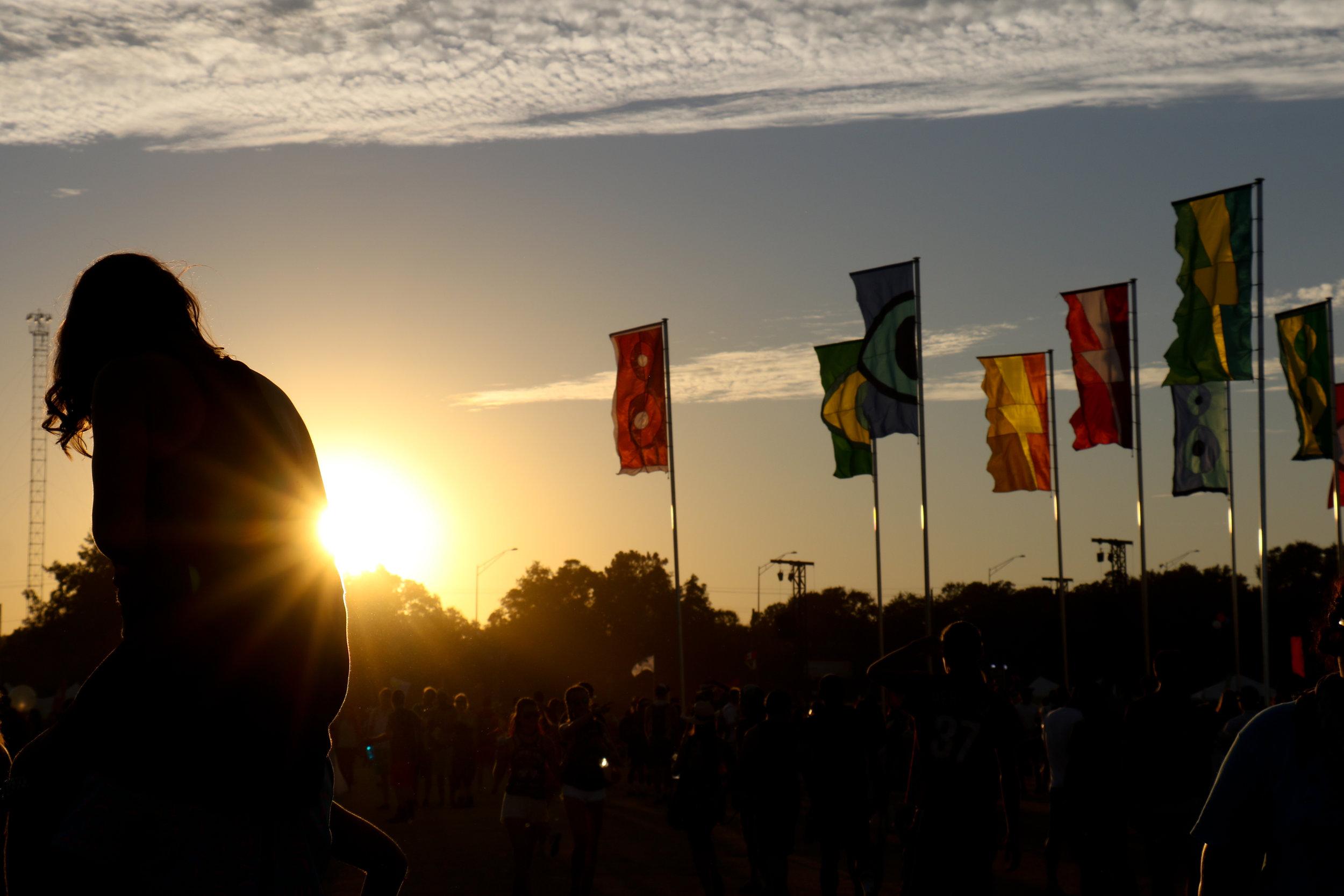   A festival-goer overlooks the festival from her friend’s shoulders.  