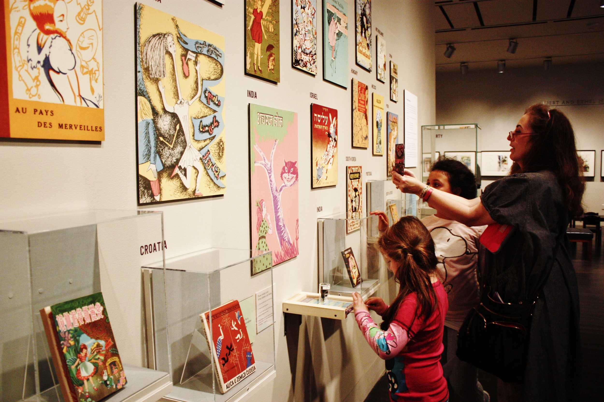  A woman and two children gaze&nbsp;at&nbsp;illustrated book covers of “Alice’s Adventure in Wonderland” from various countries.&nbsp; 