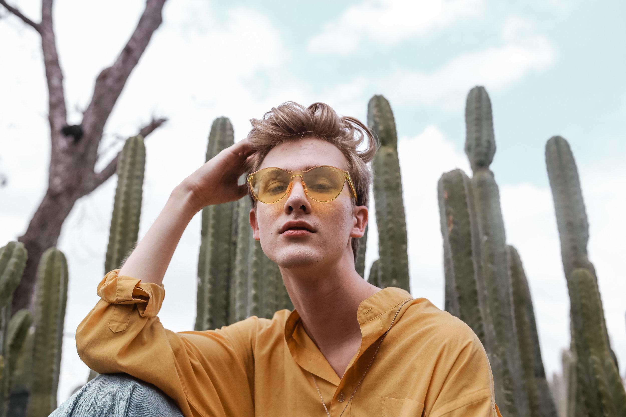   Henry Youtt wears a yellow button-up with a complimentary pair of sunglasses.  