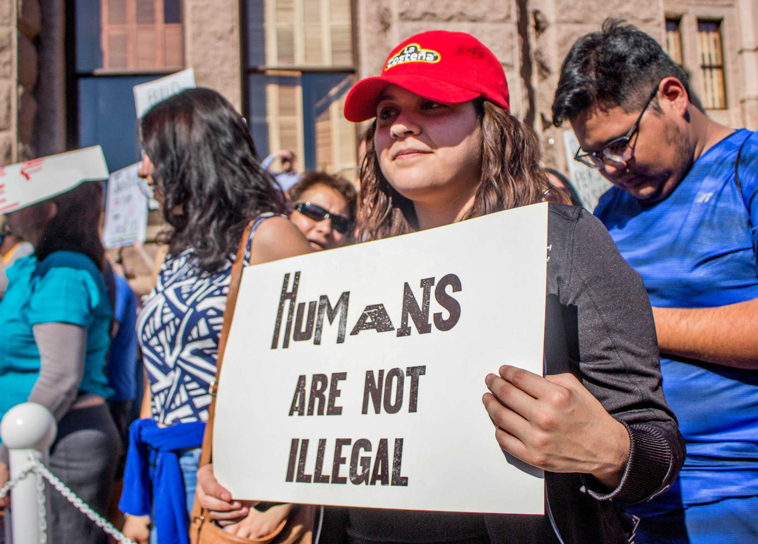   Mariana Rodriguez holds a sign that says, "Humans are not illegal" in front of the Capitol.  