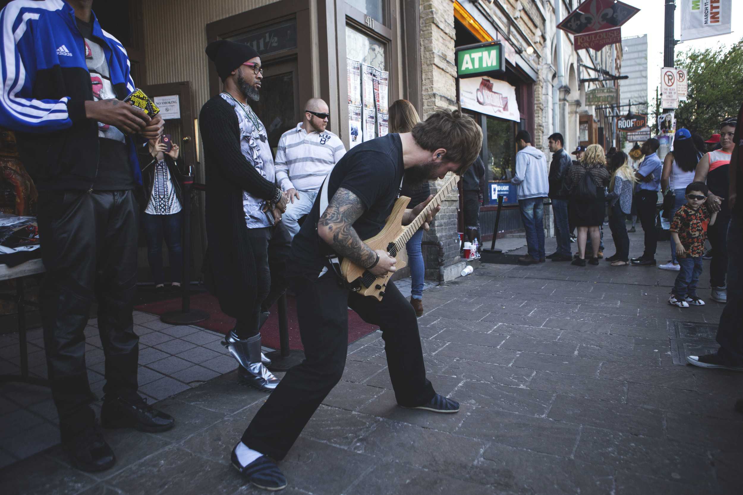  A musician runs out of a venue to perform amidst the crowds on Sixth Street on March 19. 