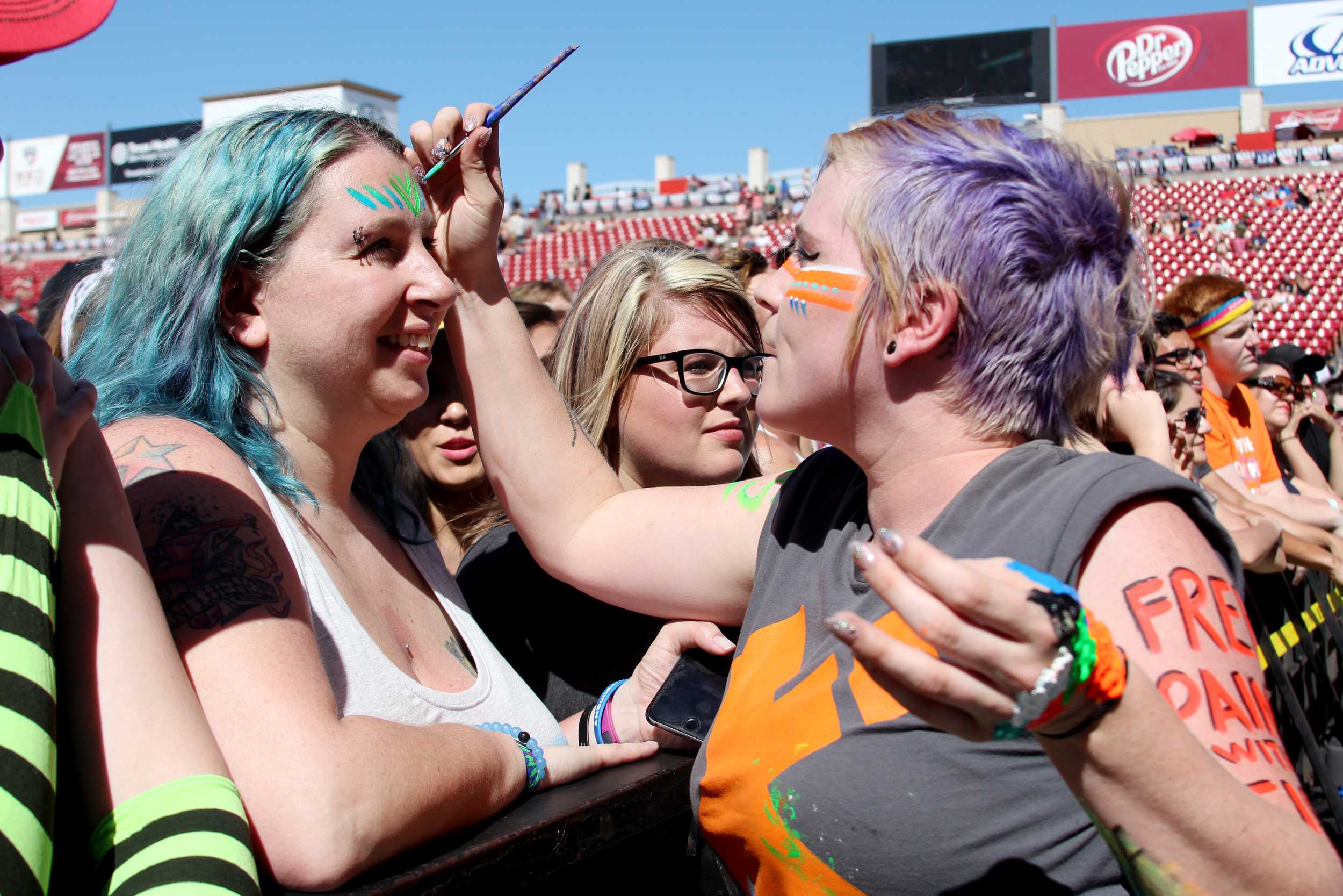   An artist paints a fan's face in the crowd.  Photo by Tess Cagle   