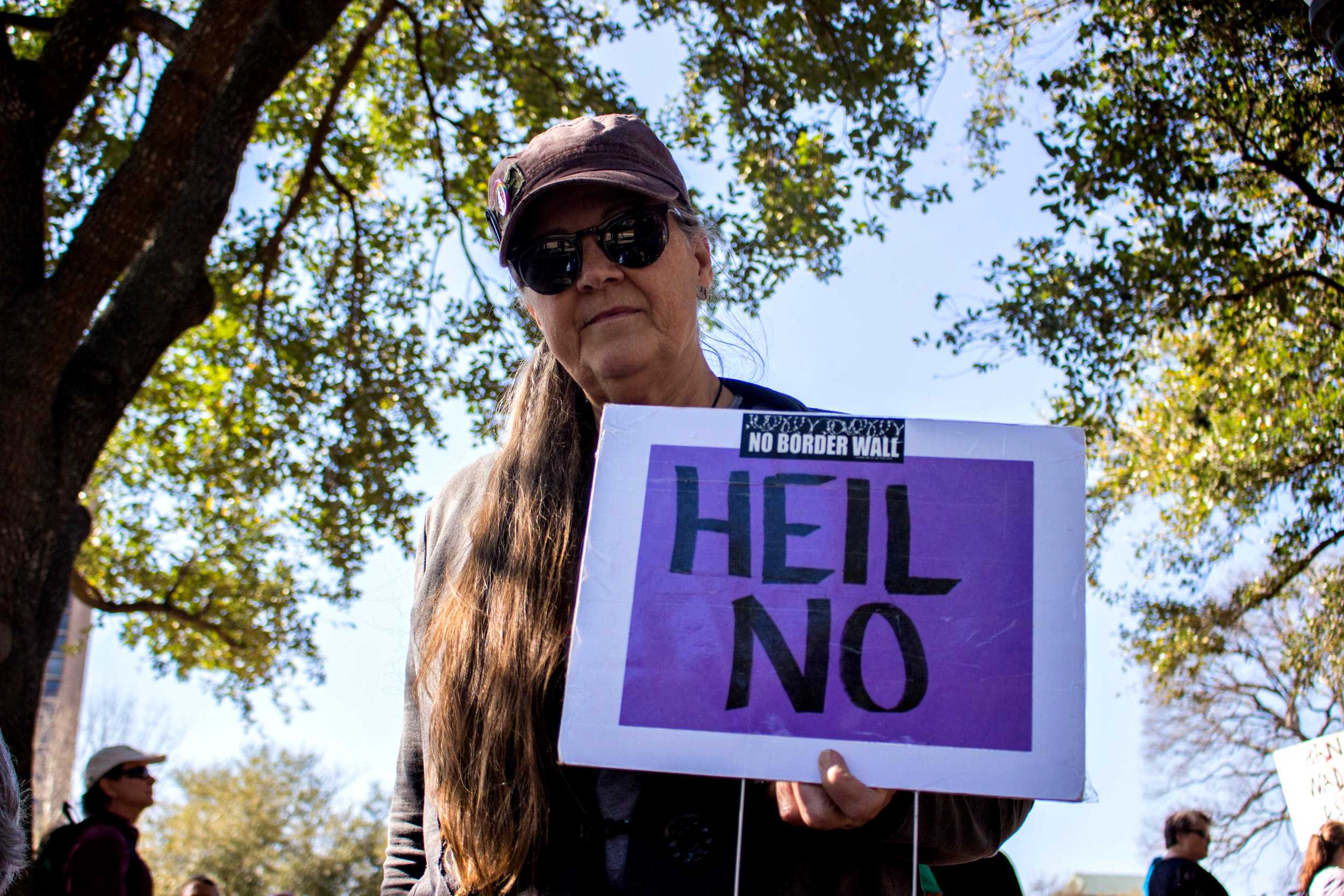   A woman at the rally holds a sign that says, "Heil no" at the "No ban, no wall" rally on Saturday.  