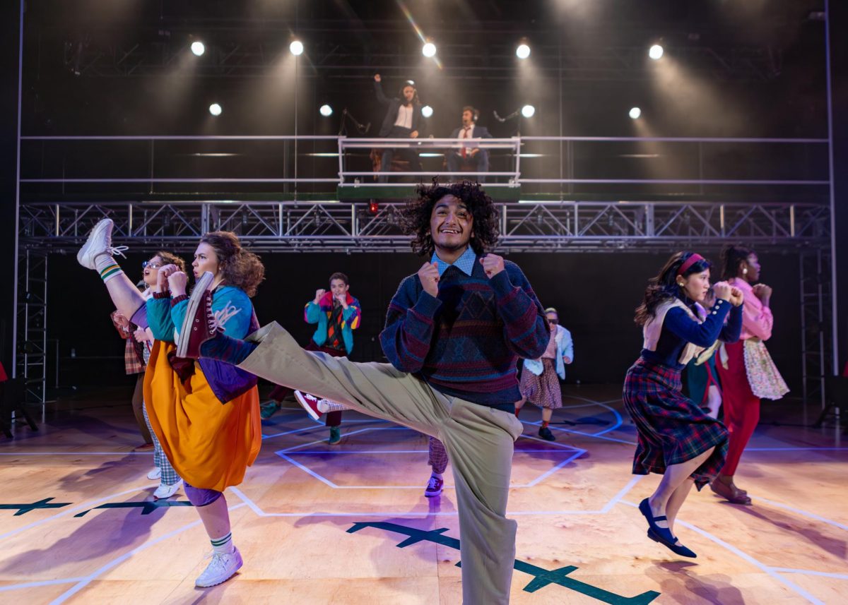 Third-year Adam Flores Jr. is flanked by the actors playing the Wembley family in “A Beautiful Day in November on the Banks of the Greatest of the Great Lakes” in the Brockett Theatre in the F. L. Winship Drama Building. (Photo by Sarah Navarrete, courtesy of the University of Texas at Austin)